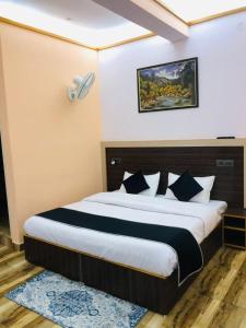 a bedroom with a large bed with black and white pillows at Goroomgo Hotel Paradise Inn Dharamshala With Luxury Mountain View Room and parking - Best Hotel in Dharamshala in Dharamshala