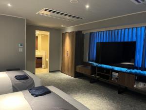 ein Hotelzimmer mit einem Bett und einem Flachbild-TV in der Unterkunft Sun Days Kagoshima in Kagoshima