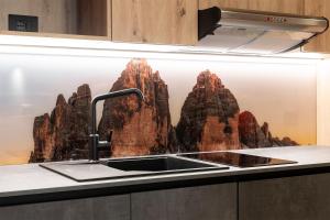 a kitchen sink with a mural of mountains at Zur Brücke in Mittewald - Your home in heart of South Tyrol, with Brixencard and free parking, ideal starting point for unforgettable excursions and outdoor adventures in Fortezza