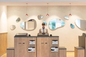 a woman standing at a counter in a room with mirrors at Sun Days Kagoshima in Kagoshima