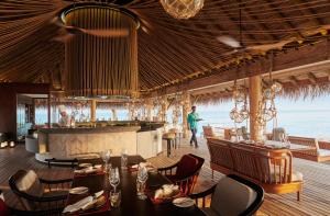 a restaurant with tables and chairs and a bar at Sirru Fen Fushi Maldives in Shaviyani Atoll