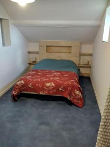 een slaapkamer met een bed met een rode deken bij Gîte LE LOFT chez Judith et Neiges 
