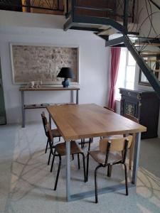 een houten tafel en stoelen in een kamer bij Gîte LE LOFT chez Judith et Neiges 
