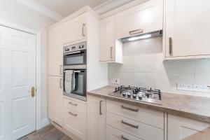 cocina con armarios blancos y fogones en 6 Meadowcroft House, en Bowness-on-Windermere