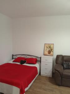 um quarto com uma cama com um cobertor vermelho e uma cadeira em Апартамент в Новобудові Стрийська Автовокзал em Lviv