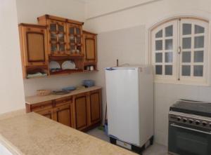 a kitchen with a white refrigerator and wooden cabinets at Mountain View Apartments Hotel in Al Aqālitah