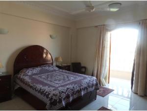 a bedroom with a bed and a large window at Mountain View Apartments Hotel in Al Aqālitah
