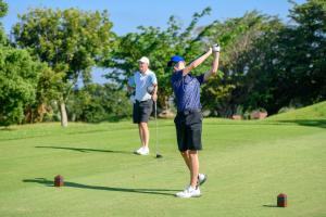 two men playing golf on a golf course at San Lameer Villa 10412 - 1 Bedroom Classic - 2 pax - San Lameer Rental Agency in Southbroom