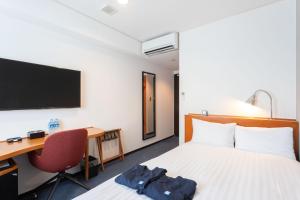 a hotel room with a bed and a desk and a tv at Sun Days Kagoshima in Kagoshima