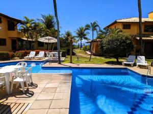 a swimming pool with a table and chairs next to a house at Residence Maria Vittoria Praia Arraial in Arraial d'Ajuda