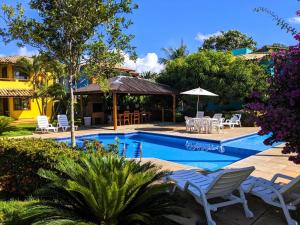 una piscina del resort con sedie, tavoli e alberi di Residence Maria Vittoria Praia Arraial a Arraial d'Ajuda