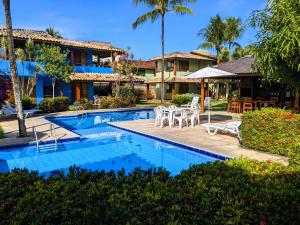 een resort met een zwembad en tafels en stoelen bij Residence Maria Vittoria Praia Arraial in Arraial d'Ajuda