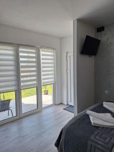 a bedroom with a bed and two windows with blinds at Apartmani Đorđević 2 in Golubac
