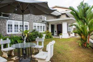 einen Tisch und Stühle mit einem Regenschirm vor einem Haus in der Unterkunft Funk Bunks - By The Lake in Kandy