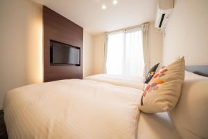 Una habitación de hotel con dos camas y un televisor. en HOME INN KUJO KAWARAMACHI, en Kioto