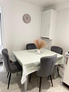 a dining room table with chairs and a clock on the wall at Stanton - Impeccable and stylish 2 bedroom in Dagenham