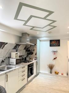 a kitchen with a sink and a microwave on a ceiling at Stanton - Impeccable and stylish 2 bedroom in Dagenham