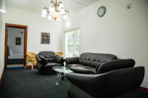 una sala de estar con 2 sofás de cuero y una mesa. en Funk Bunks - By The Lake en Kandy