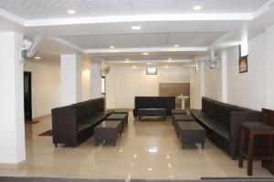 哈里瓦的住宿－Hotel Prithvi Haridwar - Excellent Stay with Family, Parking Facilities，一间设有黑色皮革沙发和桌子的等候室