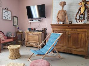 Zimmer mit Schaukelstuhl und TV in der Unterkunft Années 80, enquête et jeux hors du temps in Saint-Romain-le-Preux