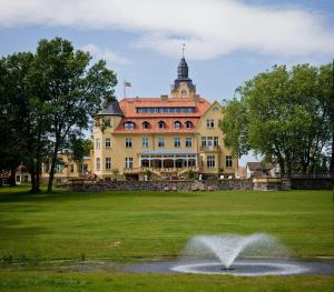 a large building with a fountain in the middle of a park at Bernsteinschloss in Wendorf