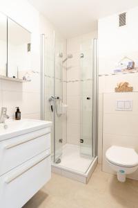 a white bathroom with a shower and a toilet at null Haus Oland Whg 2 Südstrandkoje in Wyk auf Föhr