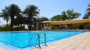 een groot blauw zwembad met een luifel en palmbomen bij Kalia Kibbutz Hotel in Kalia
