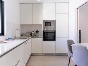 uma cozinha branca com uma mesa e um micro-ondas em Panoramic E Apartment - Rooftop Pool & Sea View & BBQ em Albufeira