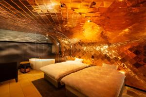 Kameya Hotel في تسوروكا: غرفة نوم بسريرين وجدار حجري