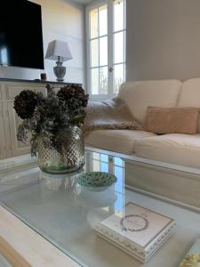 una sala de estar con una mesa de cristal con un jarrón de flores en ESPRIT CAMPAGNE, en Montpellier-de-Médillan