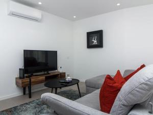 uma sala de estar com um sofá e uma televisão de ecrã plano em Panoramic E Apartment - Rooftop Pool & Sea View & BBQ em Albufeira