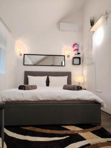 a white bedroom with a large bed with a mirror at Nyuszis Apartman in Kiskunmajsa