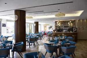 a restaurant with blue chairs and tables and a bar at Soho Midtown in Ash Shumaysānī