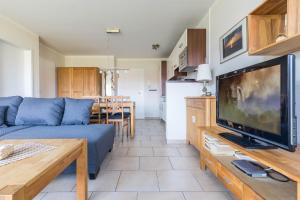 ein Wohnzimmer mit einem blauen Sofa und einem TV in der Unterkunft Haus Undine Wohnung 03 in Boltenhagen