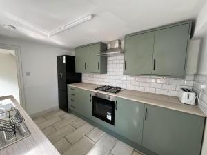 a kitchen with green cabinets and a black refrigerator at Stunning 4 BED House for Contractors & Holiday Makers in Reading