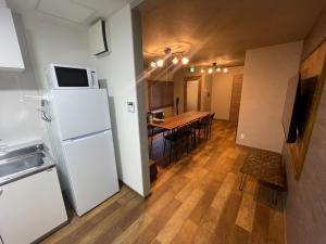 a kitchen and dining room with a white refrigerator and a table at Sofil 函館First in Hakodate