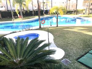 een groot zwembad met een palmboom ernaast bij STYLISH TOWNHOUSE IN BEACHFRONT COMPLEX in Marbella