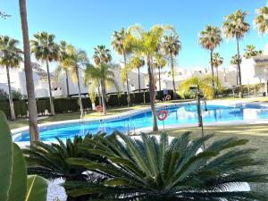 een zwembad met palmbomen in een resort bij STYLISH TOWNHOUSE IN BEACHFRONT COMPLEX in Marbella