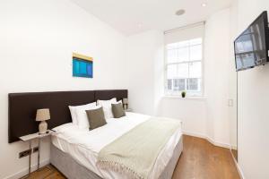 a white bedroom with a large bed and a window at JOIVY Superb Flats in the Heart of Edinburgh in Edinburgh