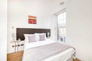 a white bedroom with a large bed and a window at JOIVY Superb Flats in the Heart of Edinburgh in Edinburgh
