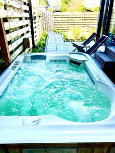 a jacuzzi tub with water in it with a bench at Tiny house with sauna & jacuzzi near Amsterdam in Vijfhuizen