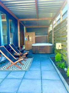 un patio con bañera de hidromasaje y 2 sillas en Tiny house with sauna & jacuzzi near Amsterdam en Vijfhuizen