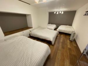 three beds in a room with white sheets at Sofil 函館First in Hakodate