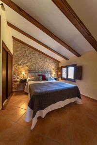 1 dormitorio con 1 cama grande en una pared de piedra en Masia Villa Pilar Valderrobres, en Valderrobres