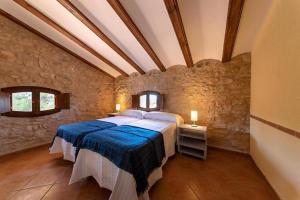 Masia Villa Pilar Valderrobres في فالديروبريس: غرفة نوم بسرير كبير في جدار حجري