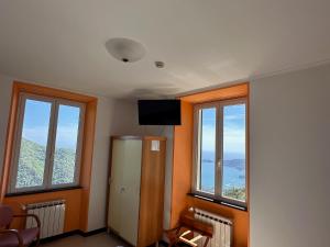 a room with two windows and a refrigerator and a television at Hotel Montallegro in Rapallo