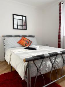 een bed in een witte kamer met een bedframe bij Eldridge Court Apartment in Dagenham