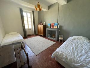 1 Schlafzimmer mit 2 Betten, einem Tisch und einem Fenster in der Unterkunft Magnifique maison Le Barroux in Le Barroux