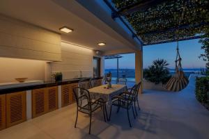 Veliko BrdoにあるFerienhaus Komplex - Villa Amelie - Makarska Exklusivのテーブルと椅子のあるキッチンとダイニングルーム