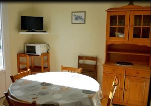 uma sala de estar com uma mesa e uma televisão e um armário em Au Pibolon des bois em Saint-Hilaire-de-Riez